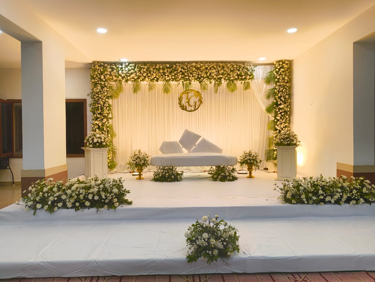 white floral stage decoration with draped backdrop and flower arrangements