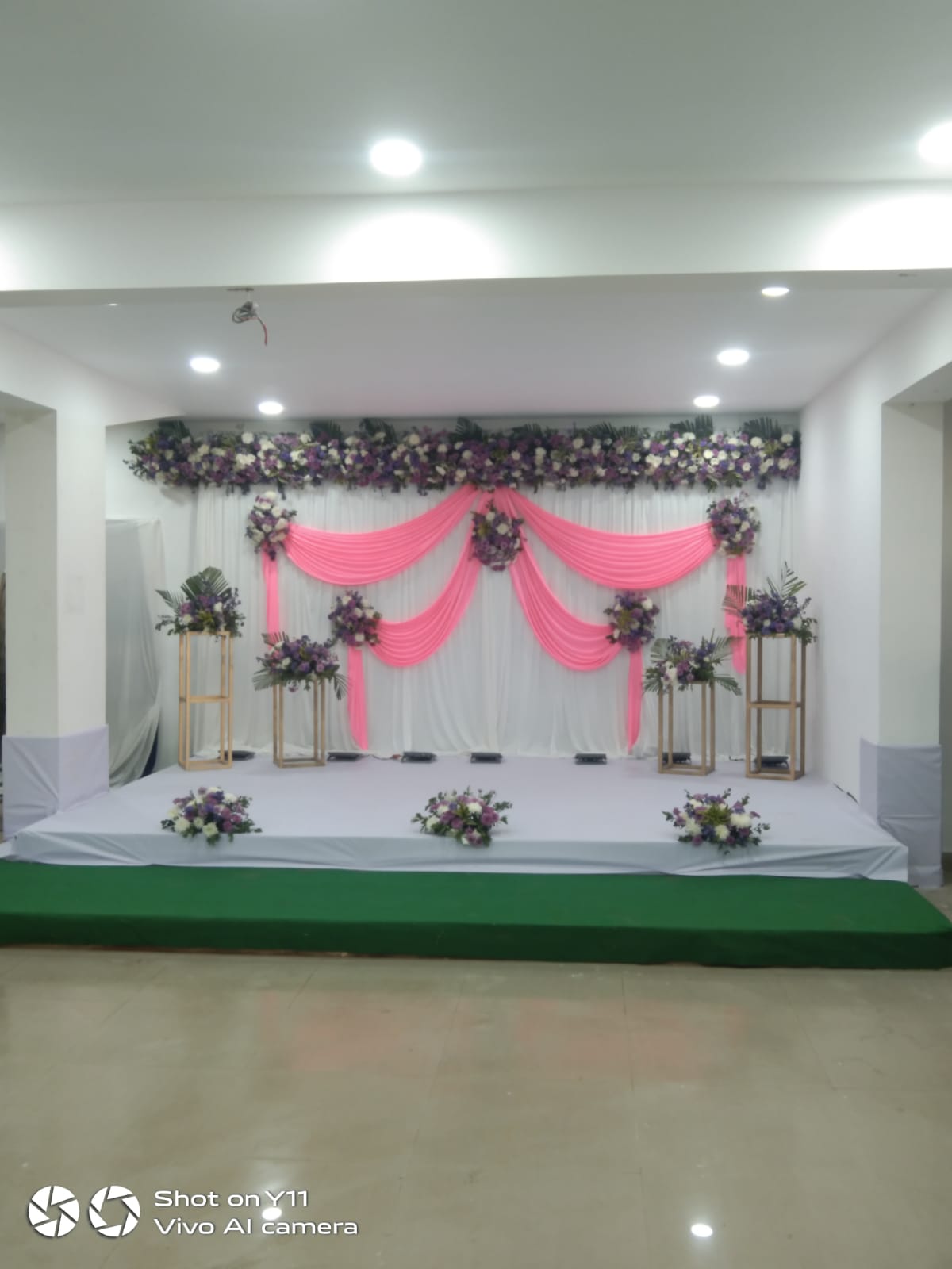 stage with pink drapes and purple and white flowers on wooden stands
