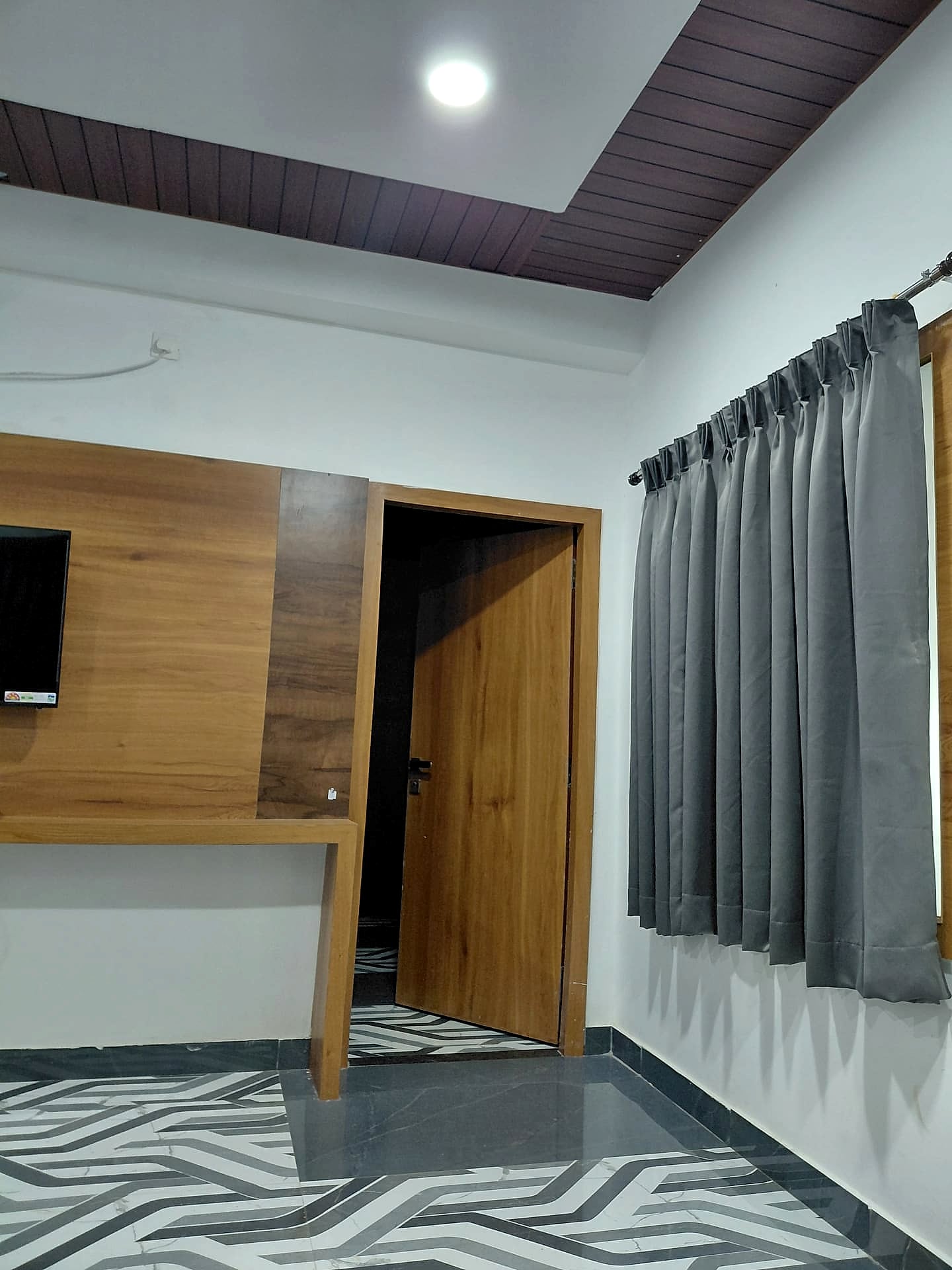 empty room corner, TV wall panel, zebra floor, no bed visible