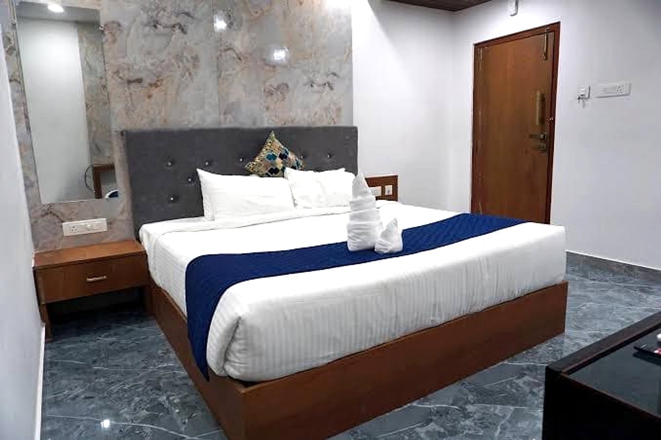 king bed, marble accent wall, grey tufted headboard, wood door