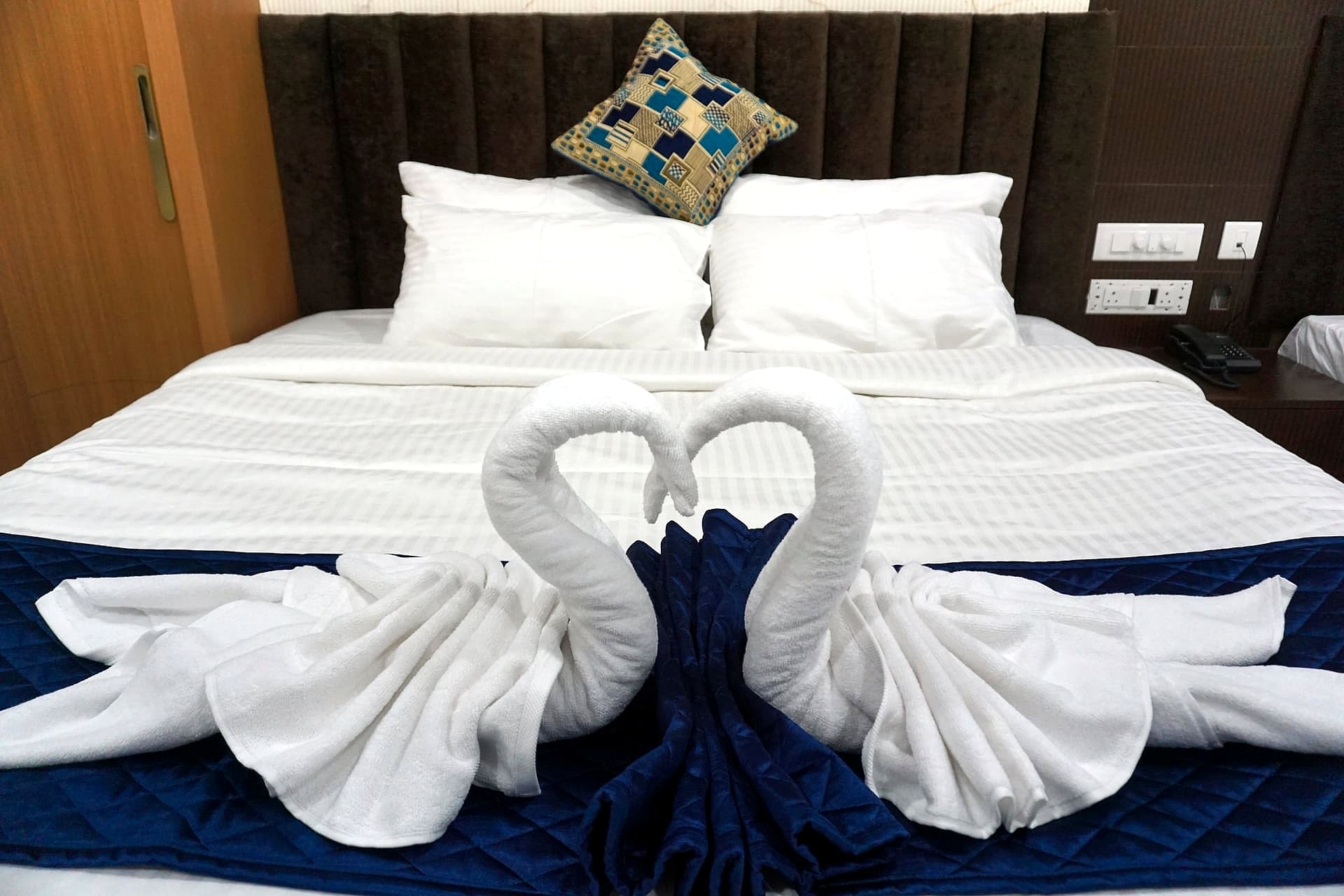 bed close-up with folded towel swans, marble headboard - detail shot